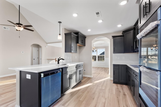 kitchen with arched walkways, light countertops, light wood-style flooring, a sink, and dishwashing machine