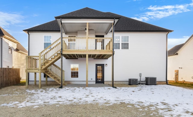 snow covered back of property featuring a shingled roof, fence, cooling unit, a wooden deck, and stairs