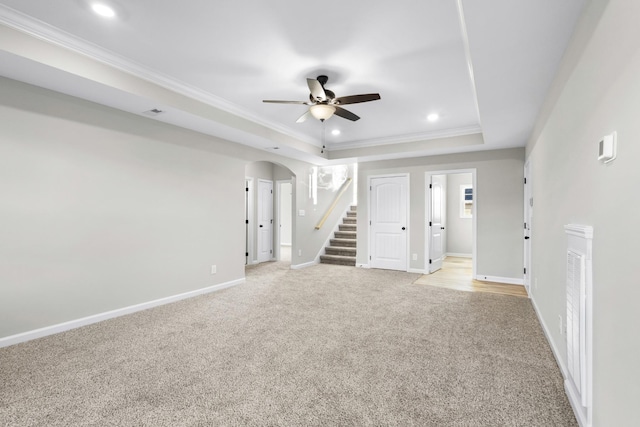 unfurnished room with baseboards, arched walkways, a raised ceiling, stairway, and ornamental molding