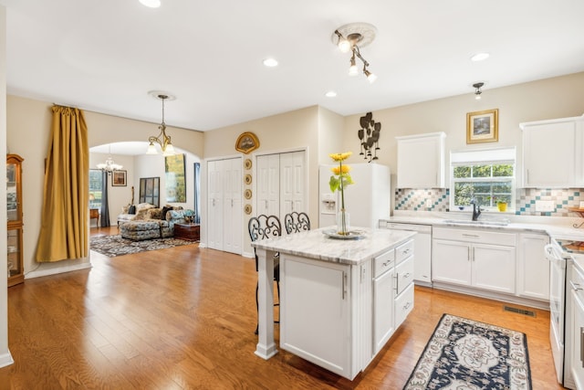 kitchen with backsplash, a center island, sink, and light hardwood / wood-style flooring