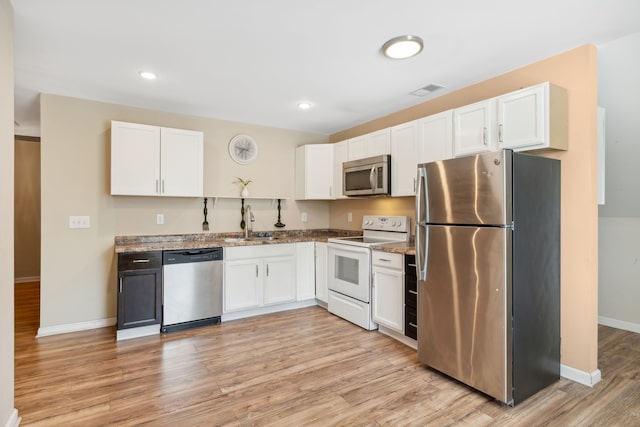 kitchen featuring stainless steel appliances, light stone counters, light wood-type flooring, and white cabinets