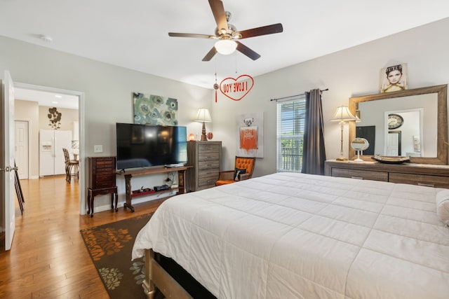 bedroom featuring hardwood / wood-style floors, ceiling fan, and white refrigerator with ice dispenser