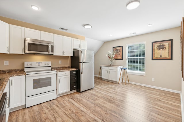 kitchen featuring light wood-type flooring, white cabinets, appliances with stainless steel finishes, and vaulted ceiling