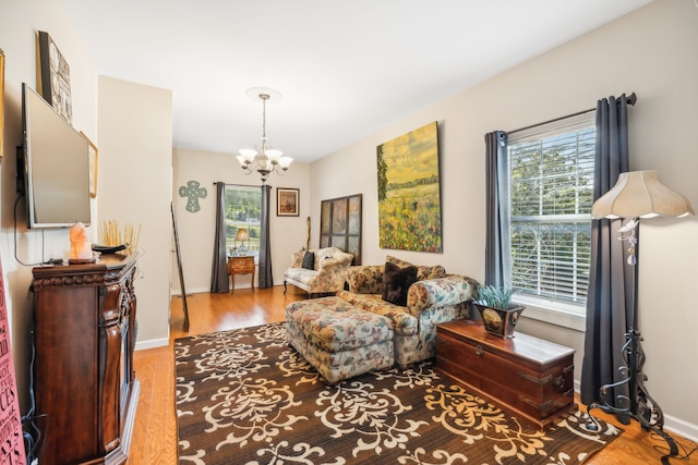 living area featuring a wealth of natural light, hardwood / wood-style floors, and a notable chandelier