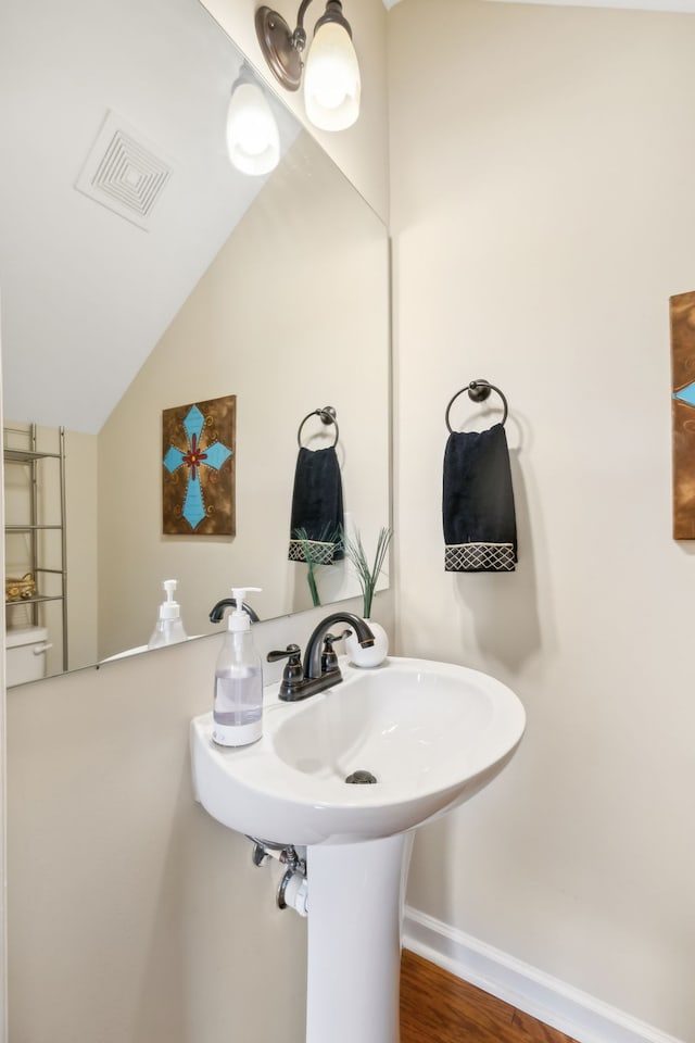 bathroom with vaulted ceiling and hardwood / wood-style floors