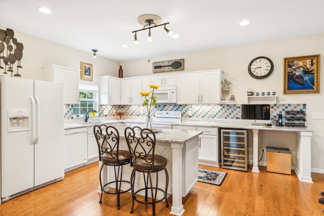 kitchen featuring a center island, light wood-type flooring, white appliances, beverage cooler, and tasteful backsplash