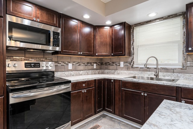 kitchen with decorative backsplash, appliances with stainless steel finishes, dark brown cabinets, and sink