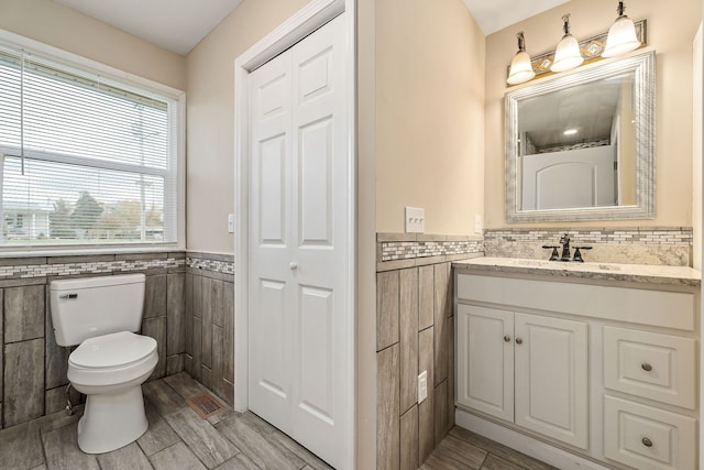 bathroom featuring vanity, hardwood / wood-style flooring, toilet, and tile walls