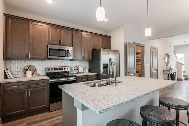 kitchen featuring appliances with stainless steel finishes, a center island with sink, hanging light fixtures, and sink