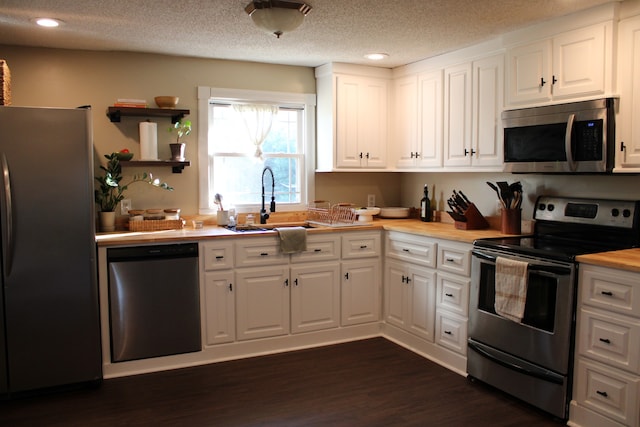 kitchen with white cabinetry, a textured ceiling, stainless steel appliances, dark hardwood / wood-style flooring, and sink