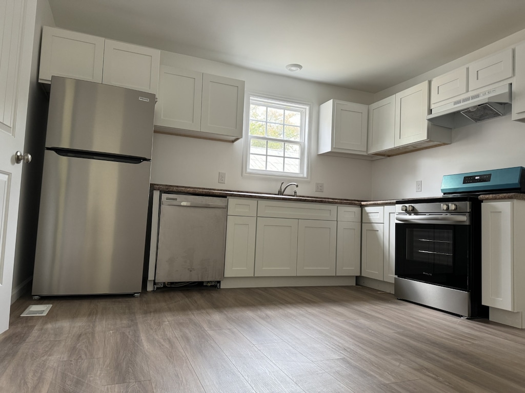 kitchen with white cabinetry, light hardwood / wood-style flooring, stainless steel appliances, and sink