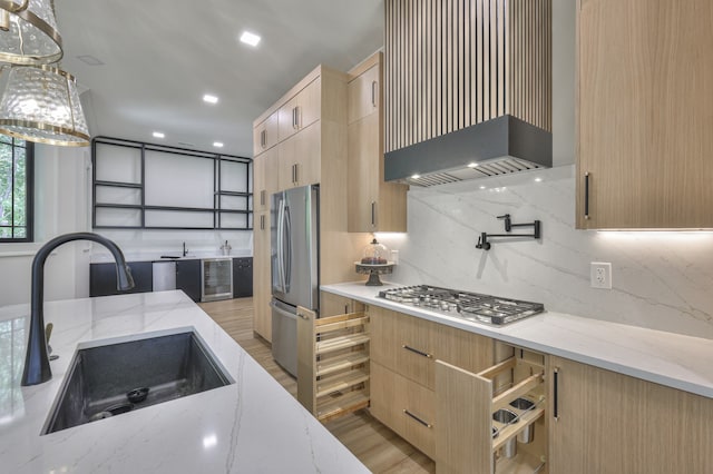 kitchen featuring beverage cooler, light stone counters, sink, decorative backsplash, and appliances with stainless steel finishes