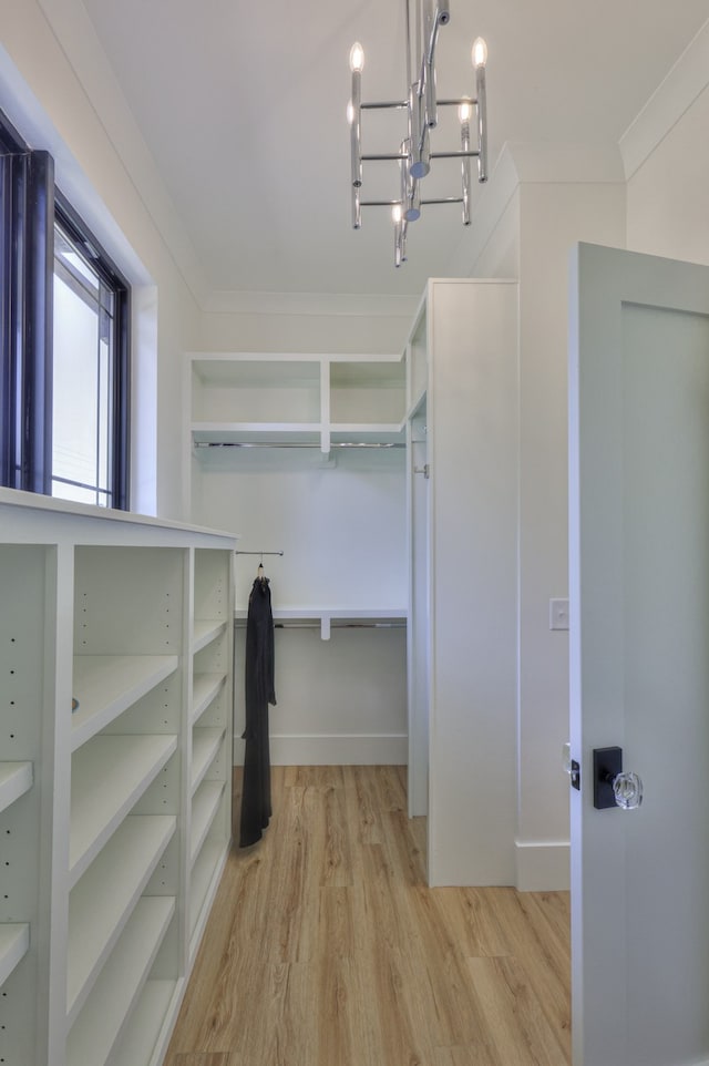 walk in closet with a notable chandelier and light wood-type flooring