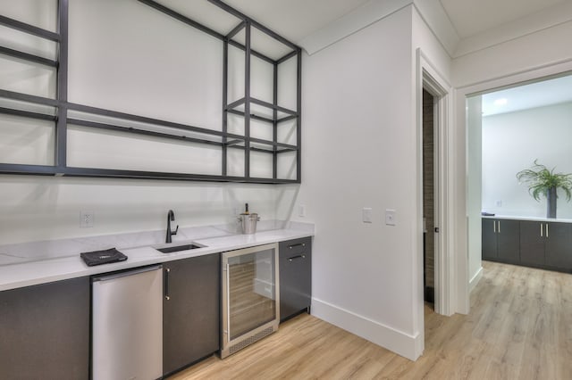 bar featuring light wood-type flooring, stainless steel fridge, wine cooler, and sink