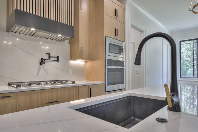 kitchen featuring appliances with stainless steel finishes, light stone countertops, wall chimney exhaust hood, and tasteful backsplash