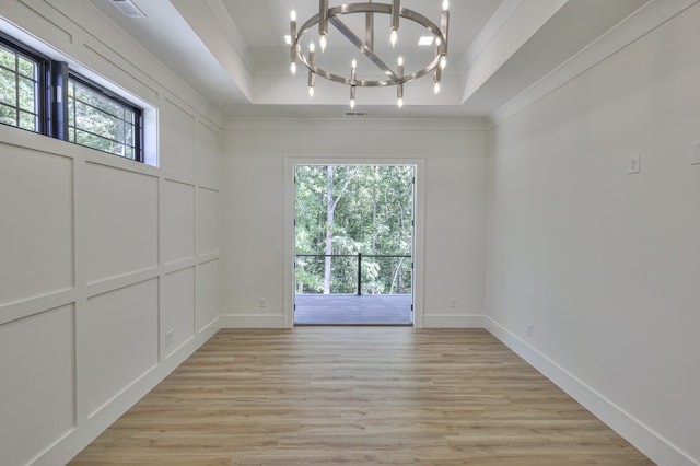 unfurnished room with plenty of natural light, a tray ceiling, and light hardwood / wood-style floors