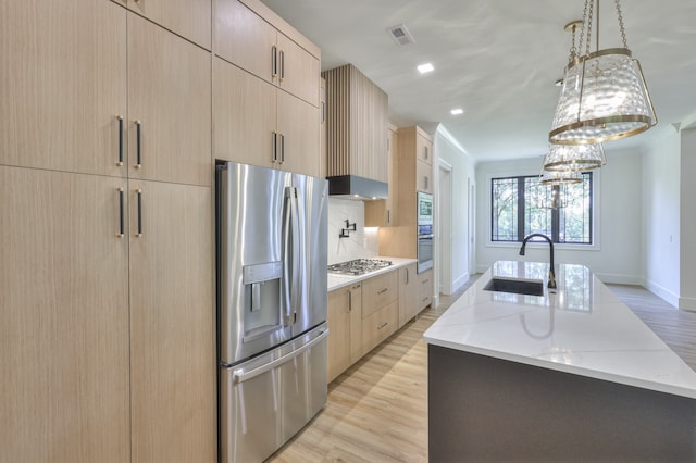 kitchen featuring hanging light fixtures, stainless steel appliances, light stone countertops, and light wood-type flooring