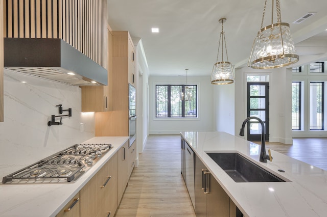 kitchen featuring tasteful backsplash, light hardwood / wood-style flooring, sink, and light stone countertops