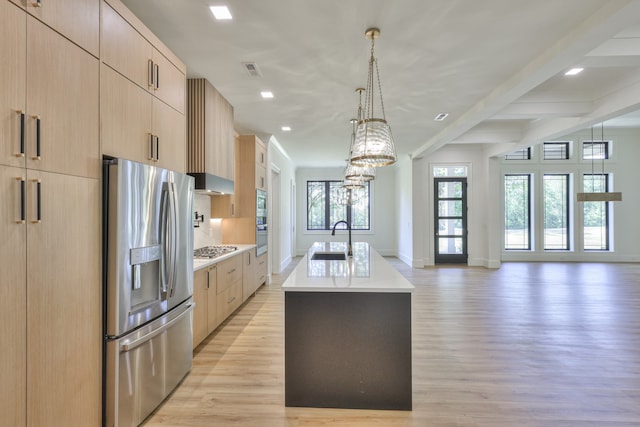 kitchen featuring light hardwood / wood-style flooring, light brown cabinetry, sink, appliances with stainless steel finishes, and a center island with sink