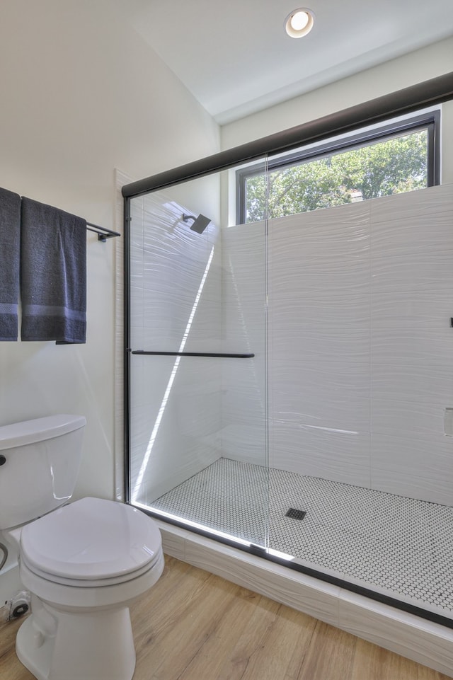 bathroom featuring plenty of natural light, toilet, wood-type flooring, and an enclosed shower