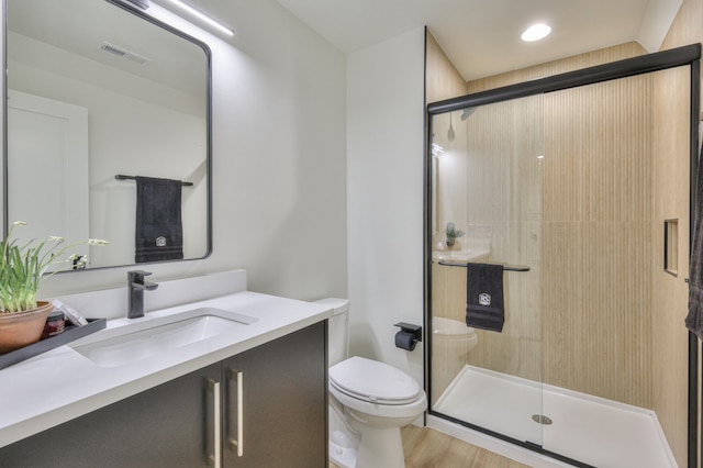 bathroom featuring wood-type flooring, toilet, walk in shower, and vanity