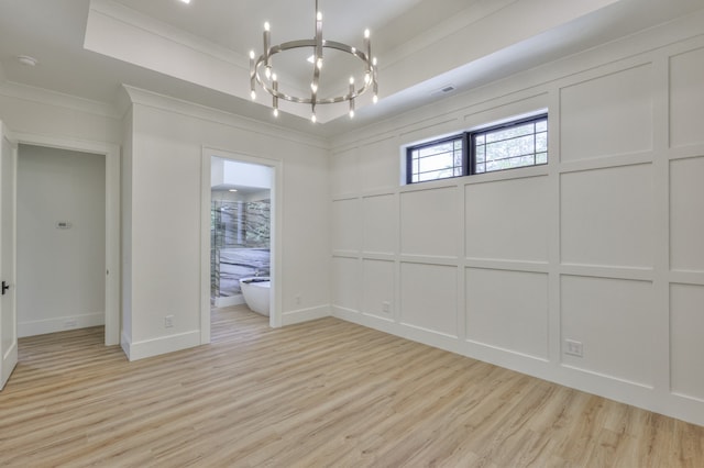 interior space featuring crown molding, a raised ceiling, a chandelier, and light hardwood / wood-style floors