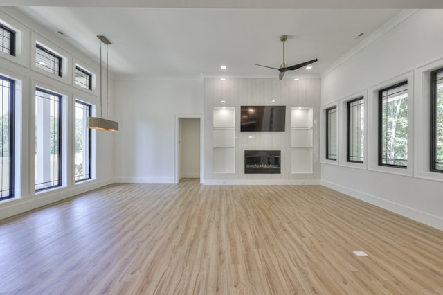 unfurnished living room with crown molding, ceiling fan, a large fireplace, and light hardwood / wood-style floors