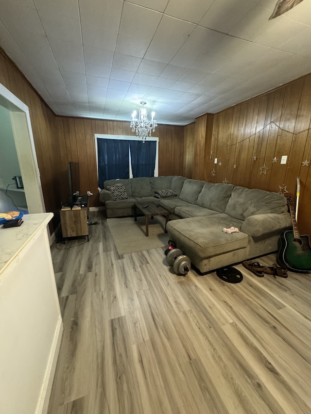 living room featuring light wood-type flooring, a notable chandelier, and wooden walls