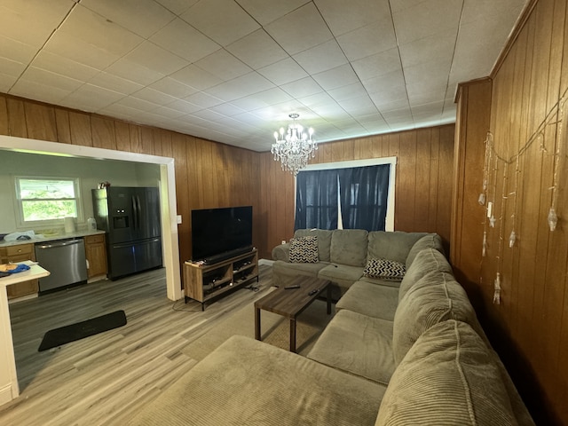 living room with light hardwood / wood-style flooring, wood walls, and a notable chandelier