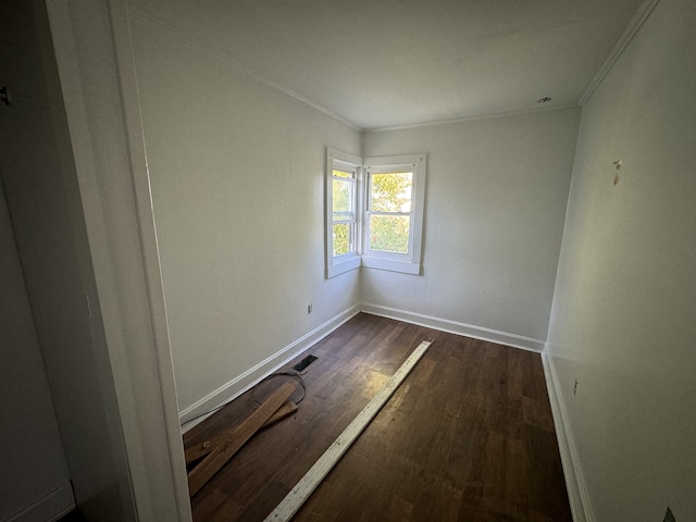 empty room with dark hardwood / wood-style floors and crown molding