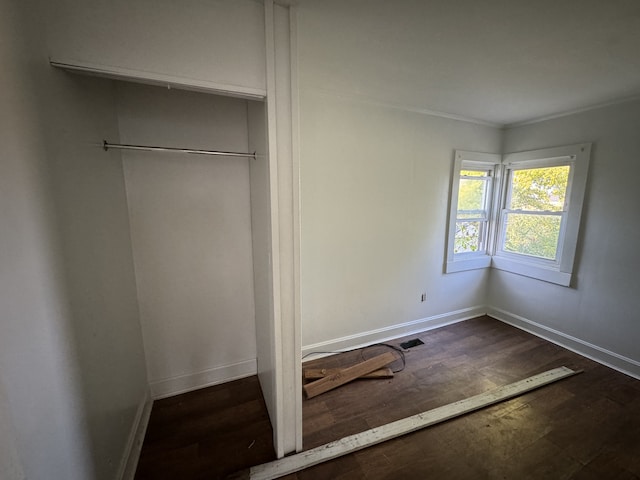 unfurnished bedroom with ornamental molding, hardwood / wood-style flooring, and a closet