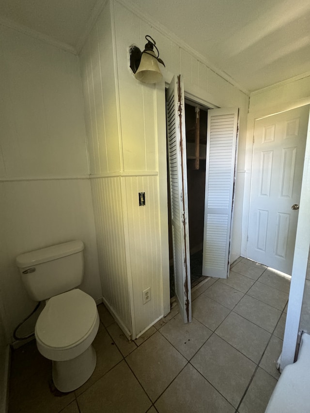 bathroom featuring toilet, ornamental molding, and tile patterned floors