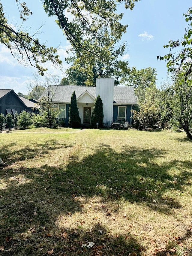 view of front facade featuring a chimney and a front yard