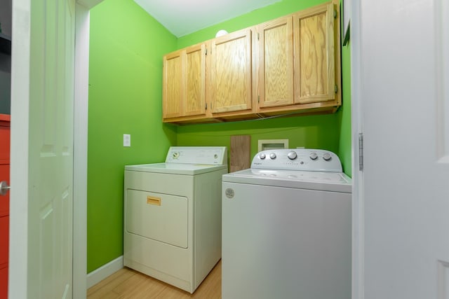 washroom featuring light wood-type flooring, cabinets, and washing machine and clothes dryer