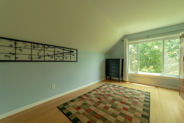 bonus room with light wood-type flooring and vaulted ceiling