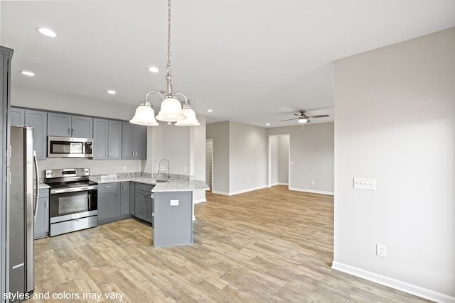 kitchen featuring kitchen peninsula, appliances with stainless steel finishes, gray cabinetry, sink, and pendant lighting