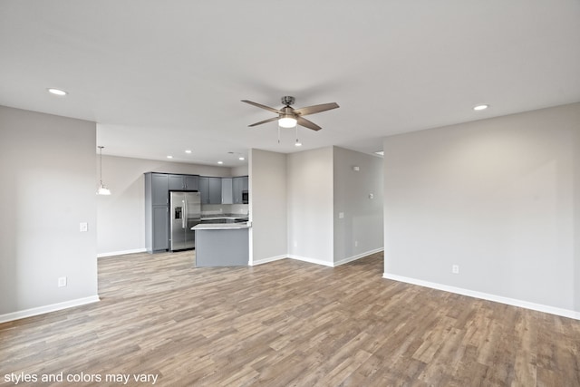 unfurnished living room featuring ceiling fan and light hardwood / wood-style floors