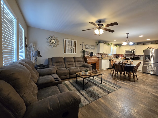 living room featuring ceiling fan with notable chandelier and wood-type flooring