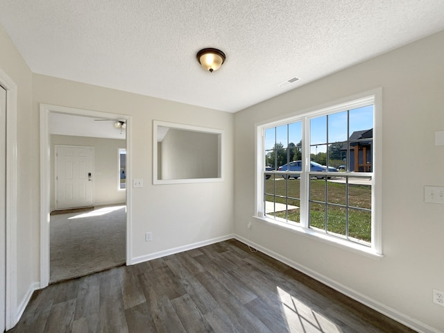 unfurnished room with a textured ceiling and dark carpet