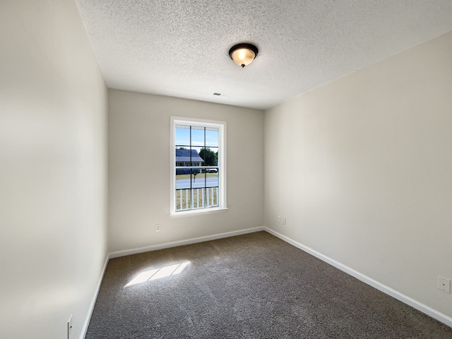 empty room with carpet and a textured ceiling