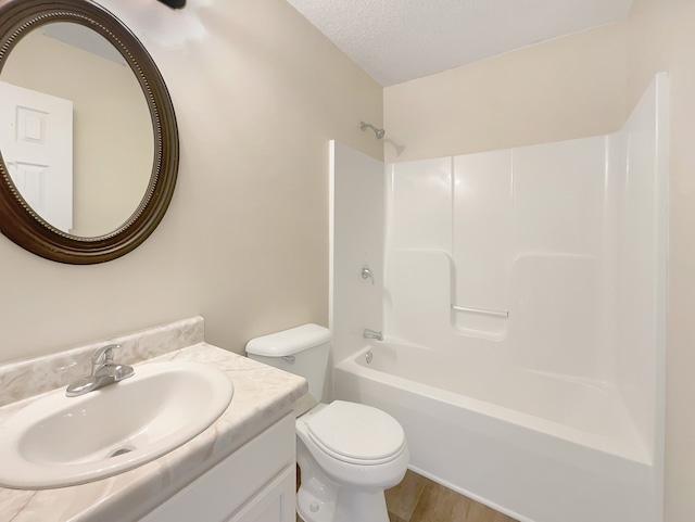 full bathroom with a textured ceiling, hardwood / wood-style floors, toilet, shower / bathing tub combination, and vanity