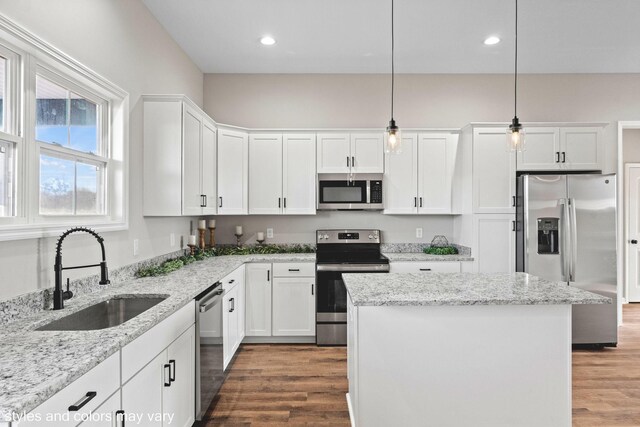 kitchen with sink, a center island, hanging light fixtures, stainless steel appliances, and white cabinets