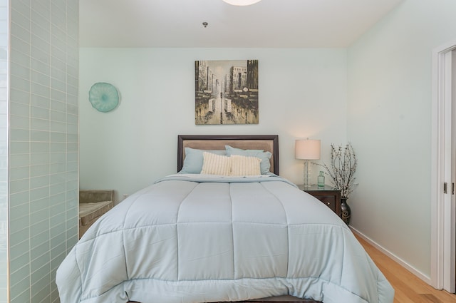 bedroom with light wood-type flooring and tile walls