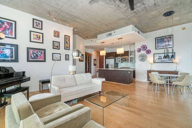 living room featuring light wood-type flooring, rail lighting, and visible vents