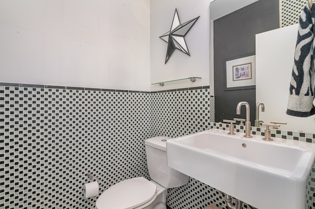 bathroom featuring tile walls, toilet, and sink