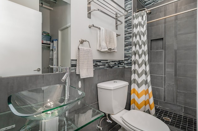 bathroom featuring curtained shower, tile walls, toilet, and sink