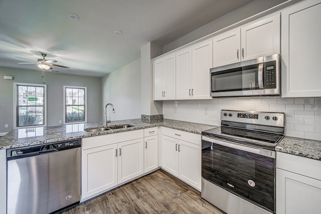 kitchen with white cabinets, hardwood / wood-style flooring, appliances with stainless steel finishes, and sink