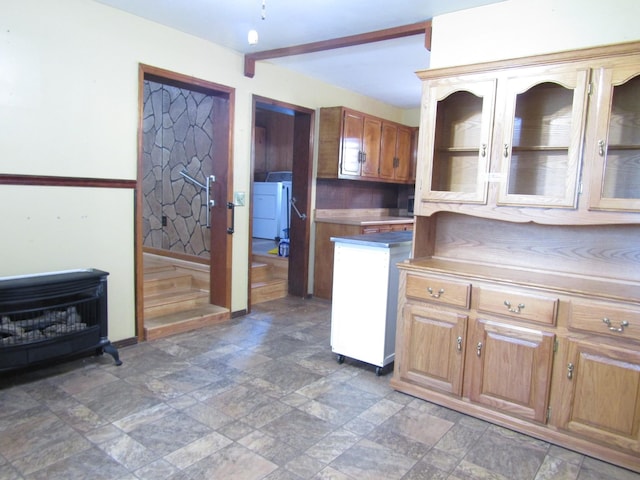 kitchen with stone finish flooring, brown cabinetry, and beamed ceiling