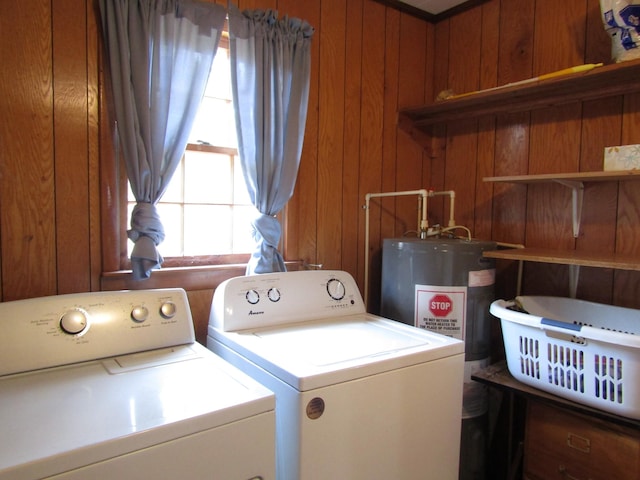 washroom featuring laundry area, separate washer and dryer, and wood walls