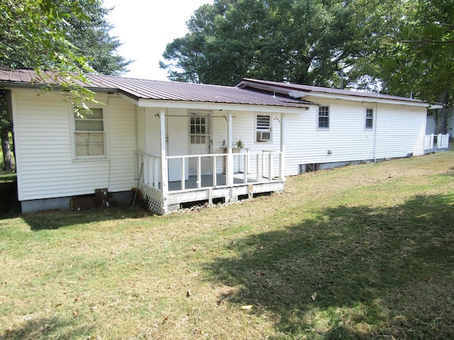 rear view of property featuring metal roof and a lawn